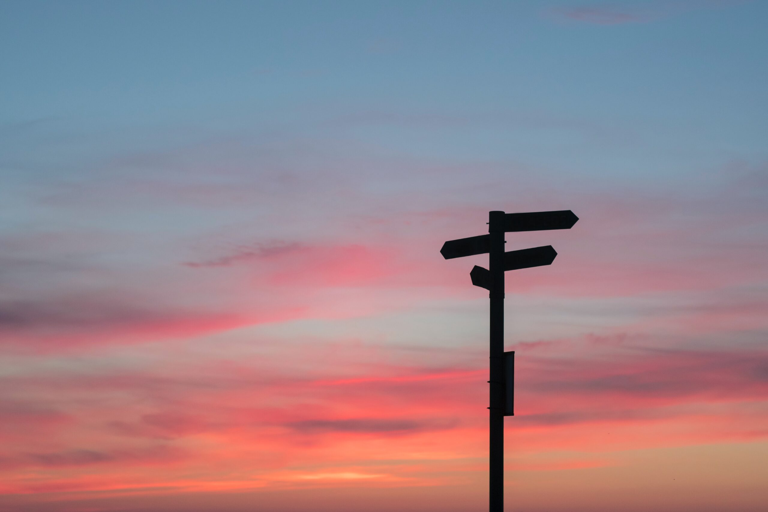 Silhouette of a signpost in front of an evening sky